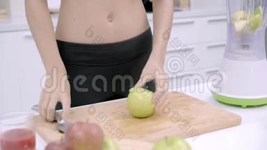 运动的亚洲女人在厨房里准备做苹果汁的配料，运动服装中的女人使用有机水果。